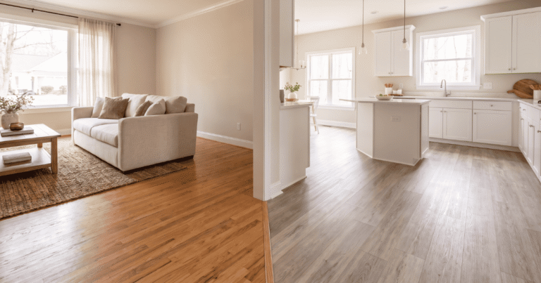 LVP flooring in a kitchen next to hardwood flooring in a living room .